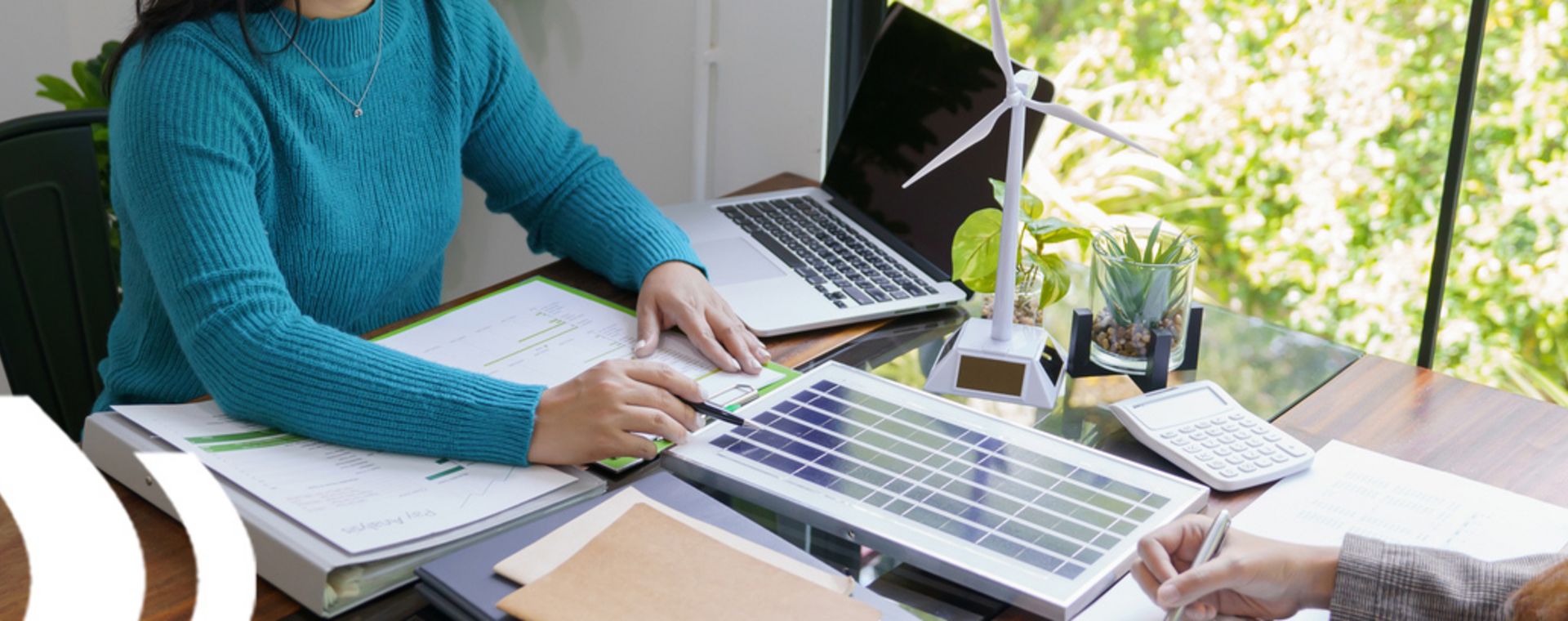 Zwei Personen am Schreibtisch mit Solarpanel, symbolisieren den Workshop zur Energieeffizienzanalyse und Implementierung eines Energiemanagementsystems.